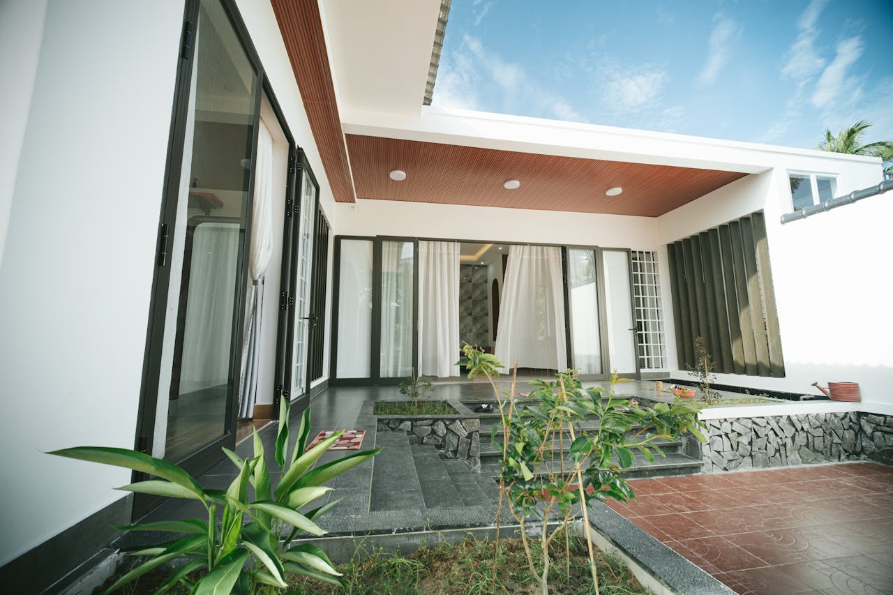 Contemporary house with glass doors, plants, and terrace under a clear sky.
